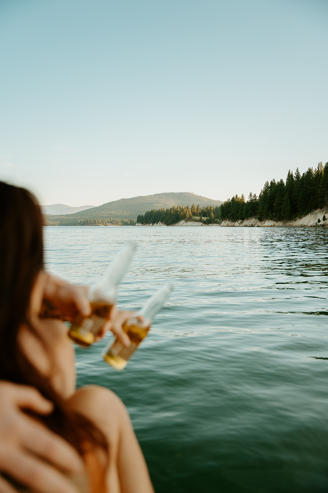 couple holding corona beers in hand over the water on the boat for their lake engagements