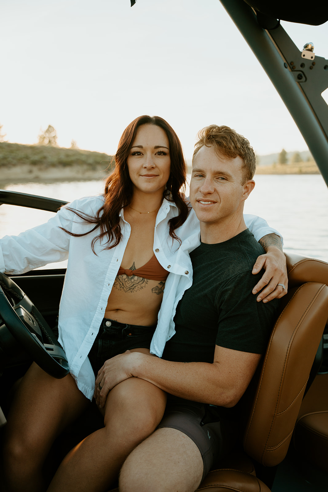 couple snuggled up at sunset during their engagement photos on their malibu boat surf boat.