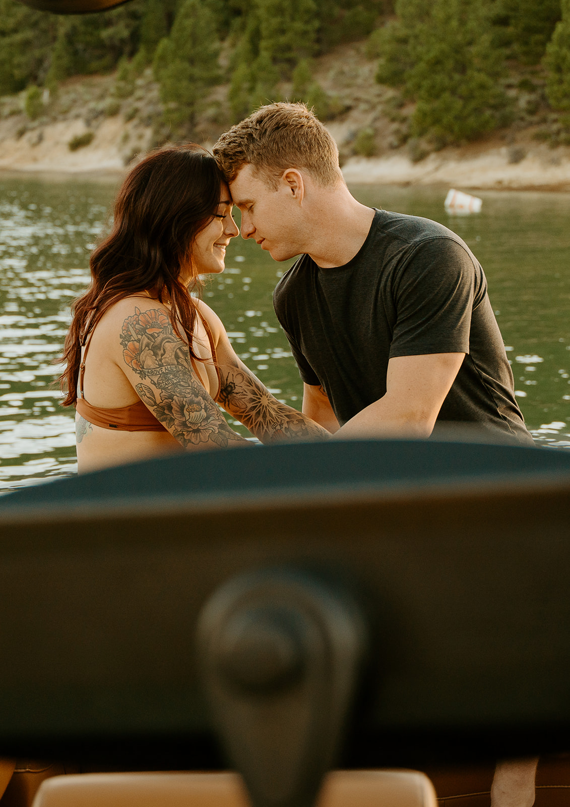 couple snuggled up at sunset during their engagement photos on their malibu boat surf boat.