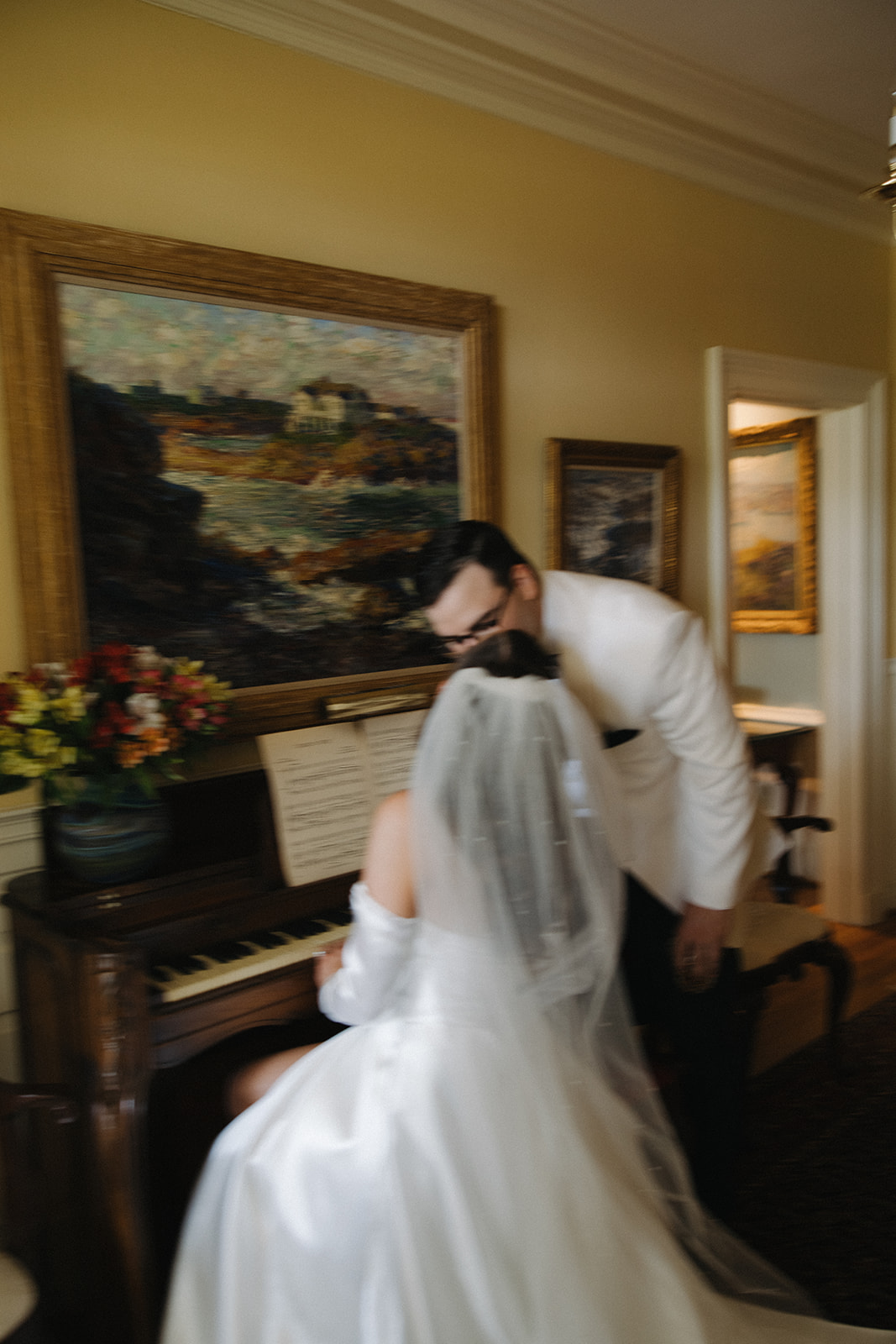 couple kisses while bride plays piano