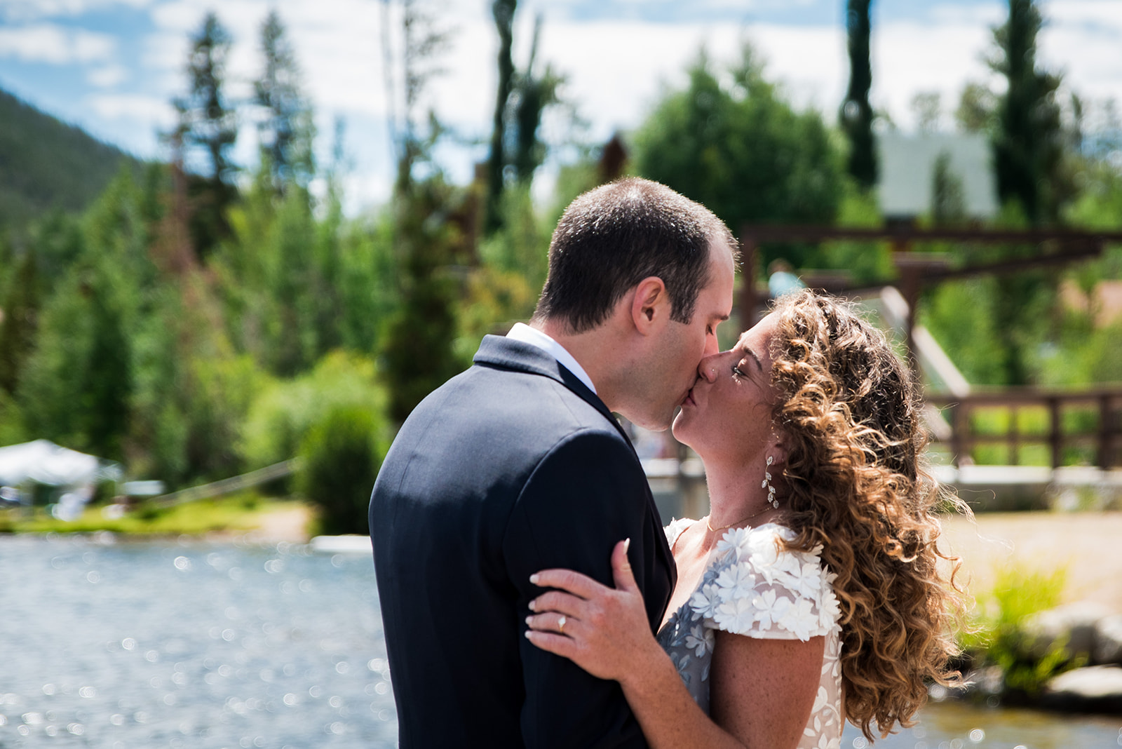Bride and groom share a kiss at Point Park in Colorado with a lake view in the background.