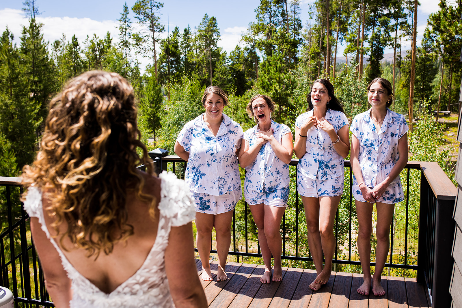 Bridesmaids react with joy to seeing bride in her dress for the first time.