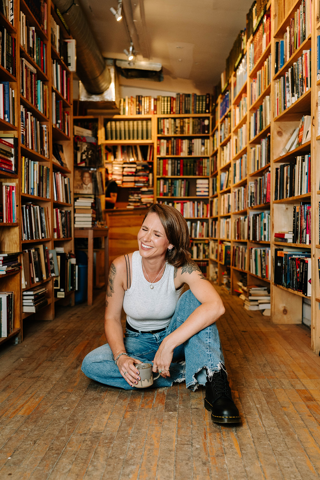 woman seated on the floor in a library while smiling off in the distance