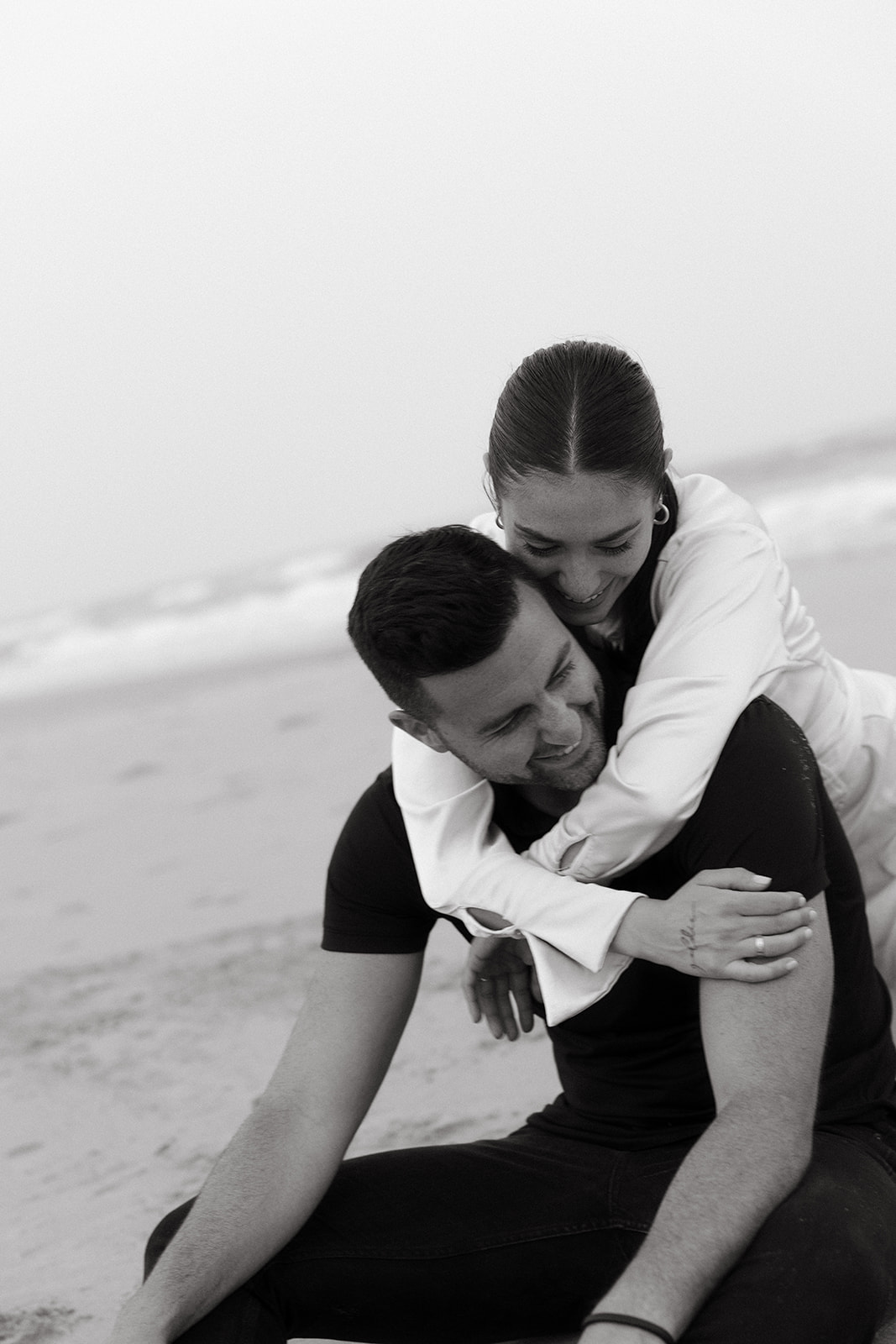 An organic couple engagement session on a New Jersey beach playing in the sand