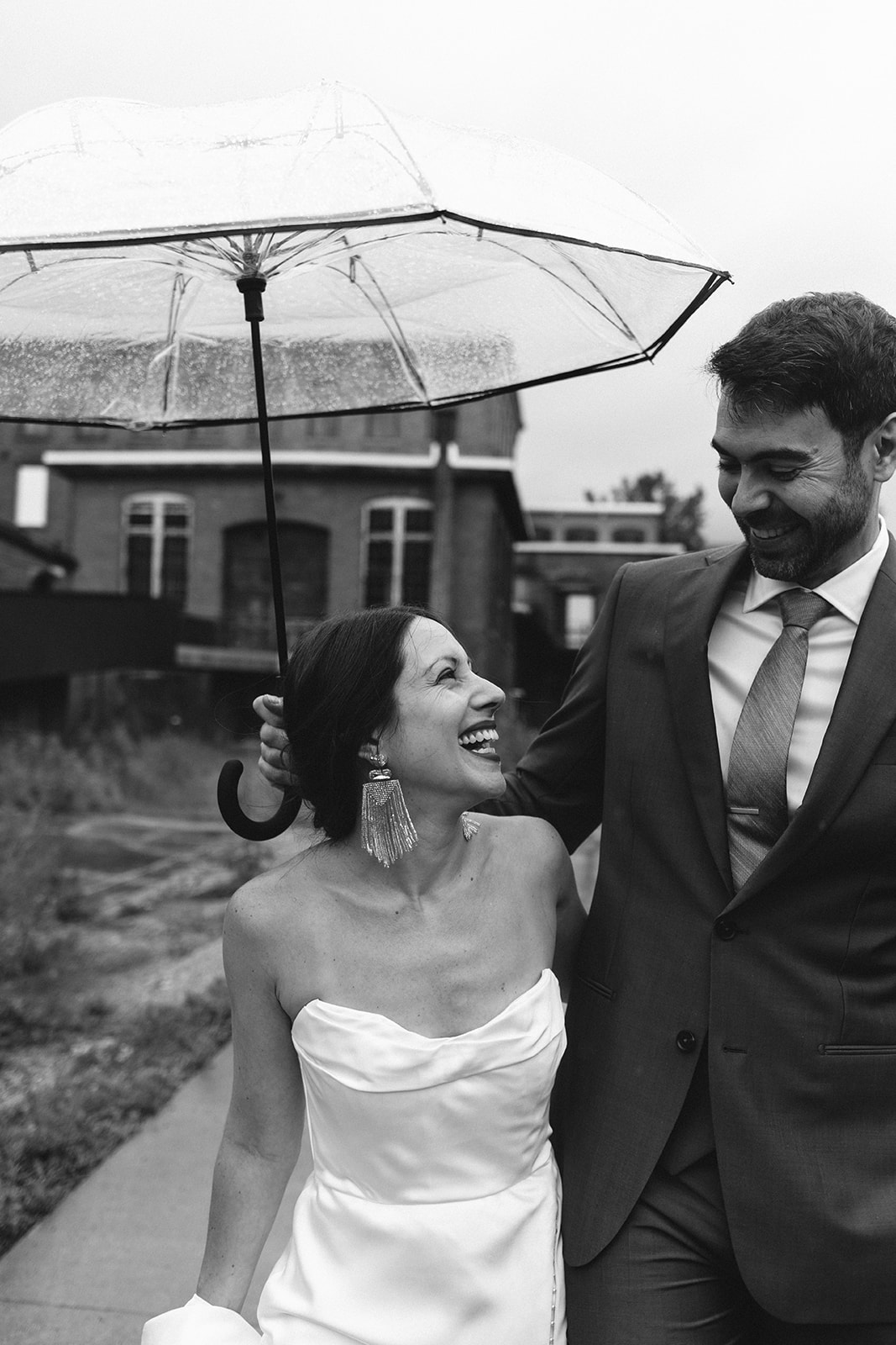 Bride and groom pose under an umbrella during their rainy wedding day at Greylock Works