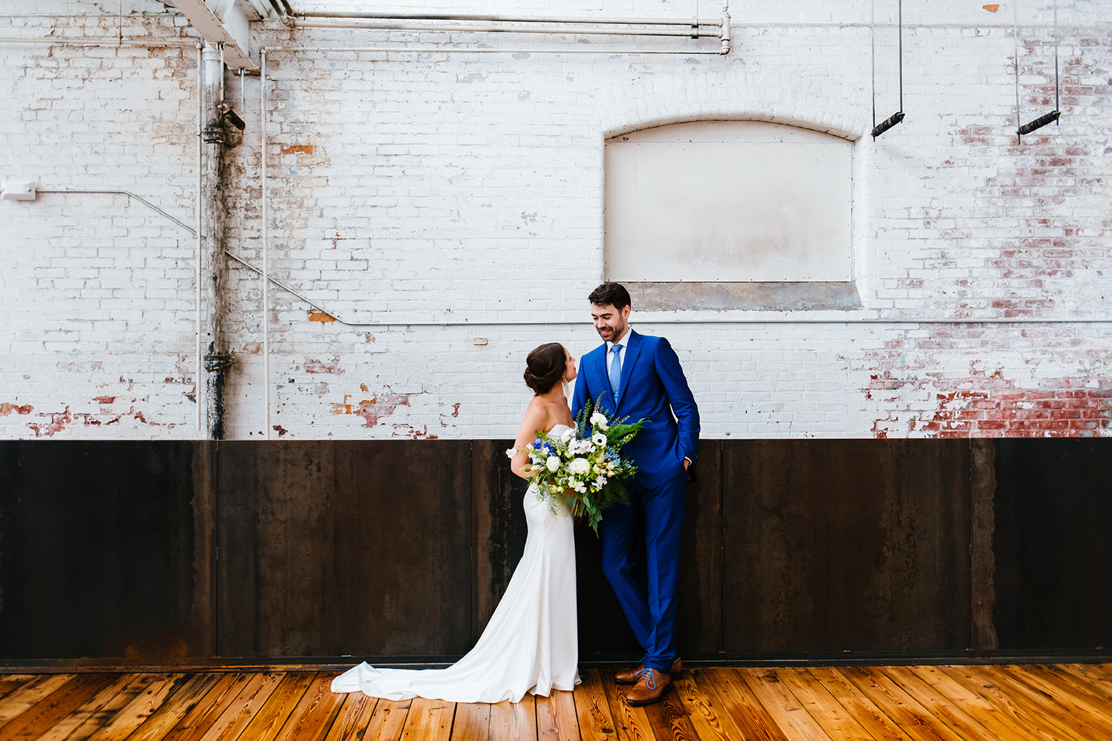 Bride and groom lean against a wall before their wedding ceremony starts.
