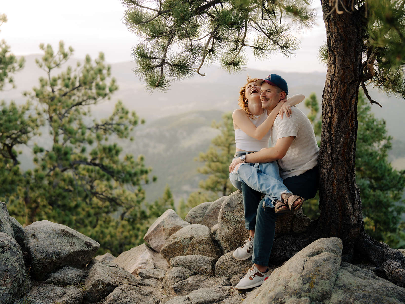 a couple sits at the top of flagstaff mountain while they love on each other for their boulder engagement session