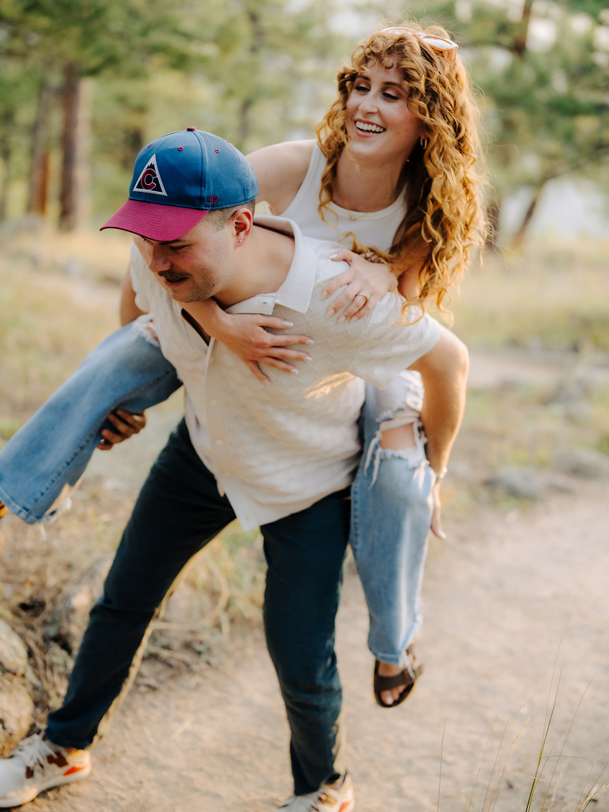 a couple gives each other piggyback rides on the top of flagstaff mountain for their boulder engagement session