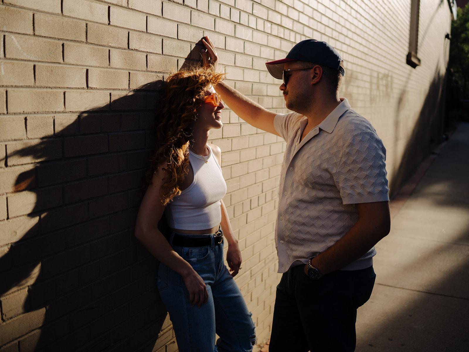 A couple looks super cool while they lean against a brick wall off of pearl street in an alley for their engagement