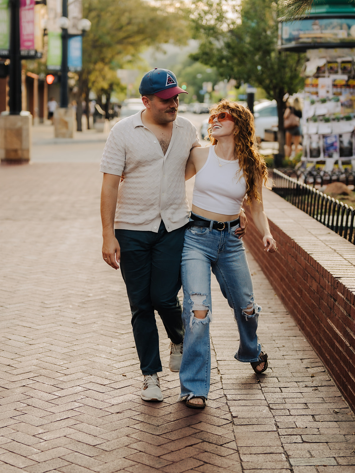 a couple walks down pearl street in boulder having fun during their engagement session in boulder co