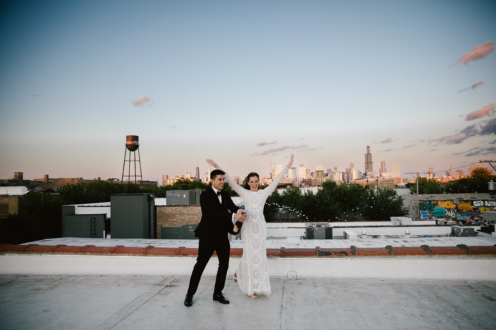 Romantic moment at Walden Chicago: Couple on rooftop at sunset, toasting with champagne against a stunning backdrop.