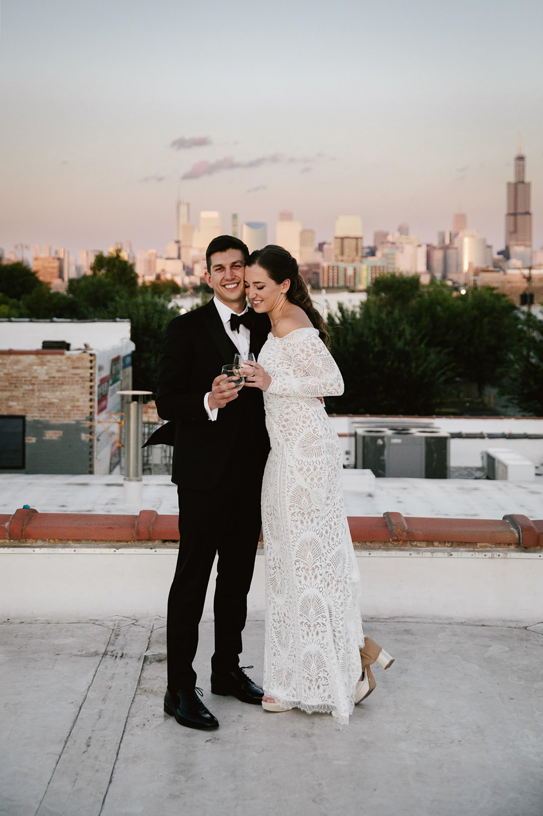 Romantic moment at Walden Chicago: Couple on rooftop at sunset, toasting with champagne against a stunning backdrop.
