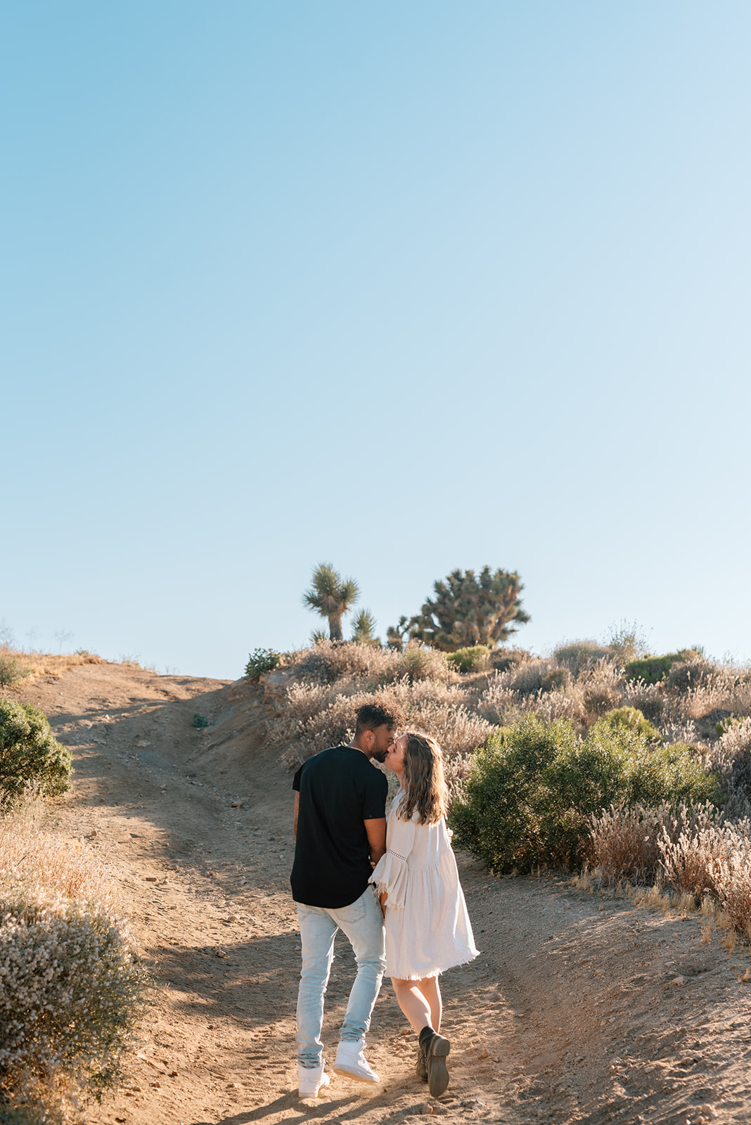 Couple walks away from the camera and into the desert