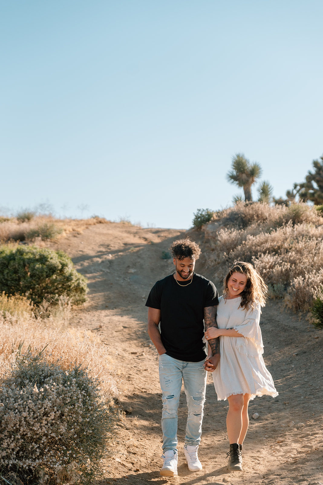 Engaged couple walks and laughs together in Joshua Tree engagement session