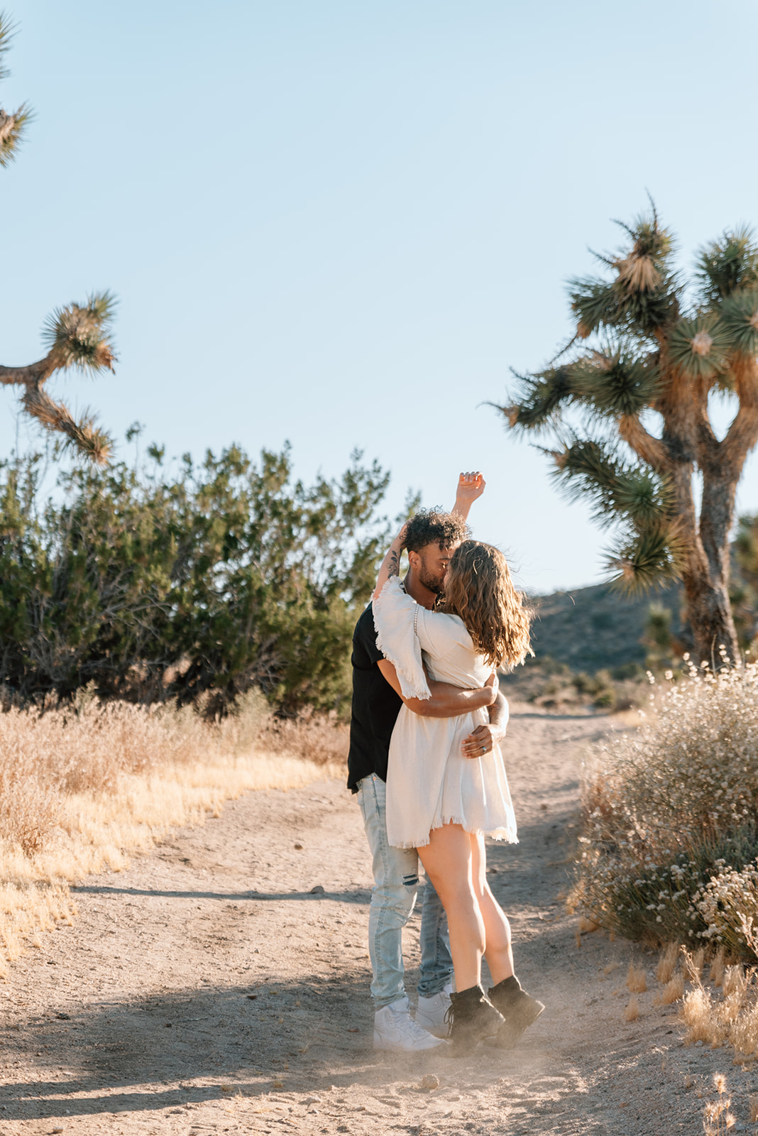 Fiances sneak a kiss on a desert path in Palm Springs California