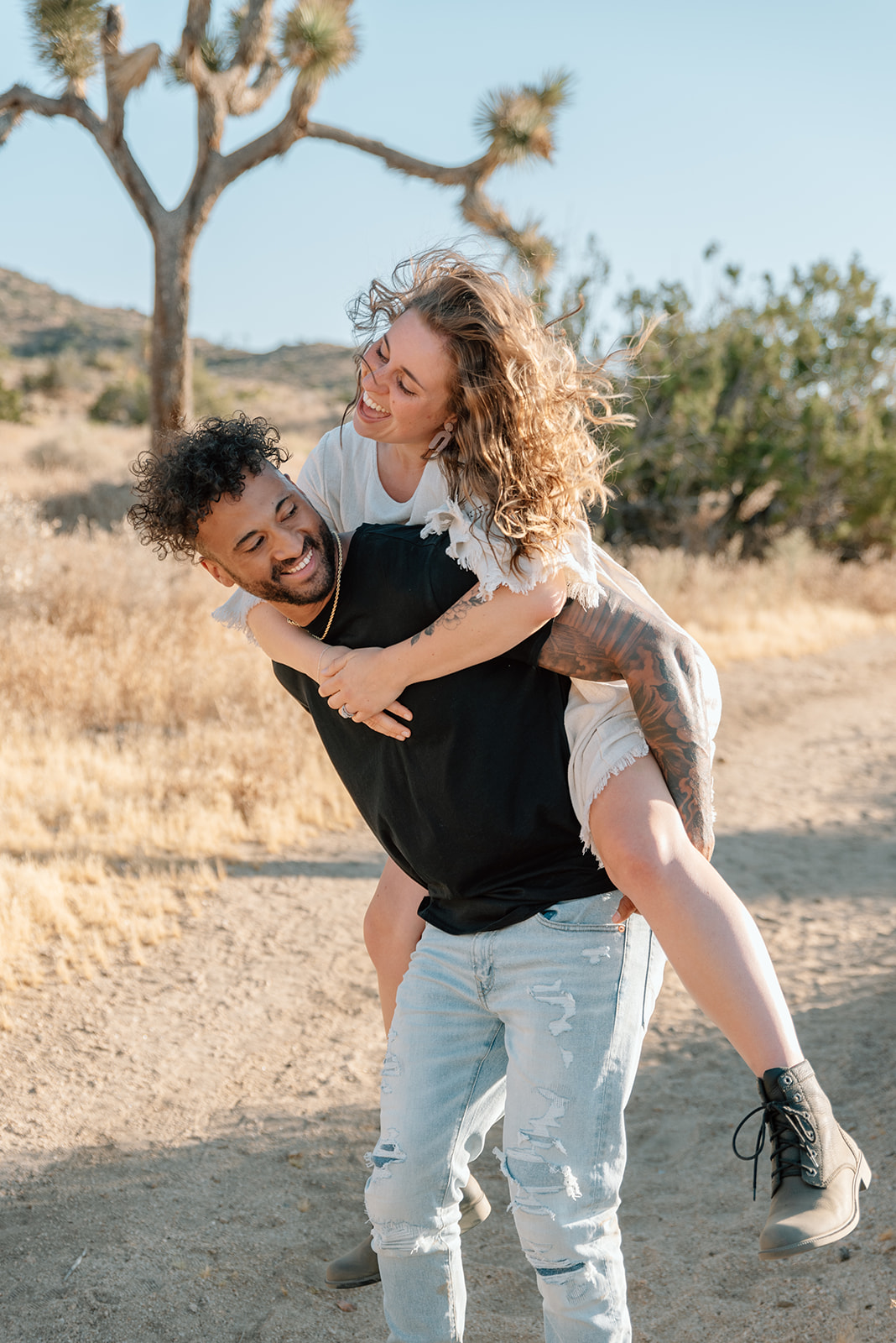 Piggyback ride in the desert during engagement session cactus in the background