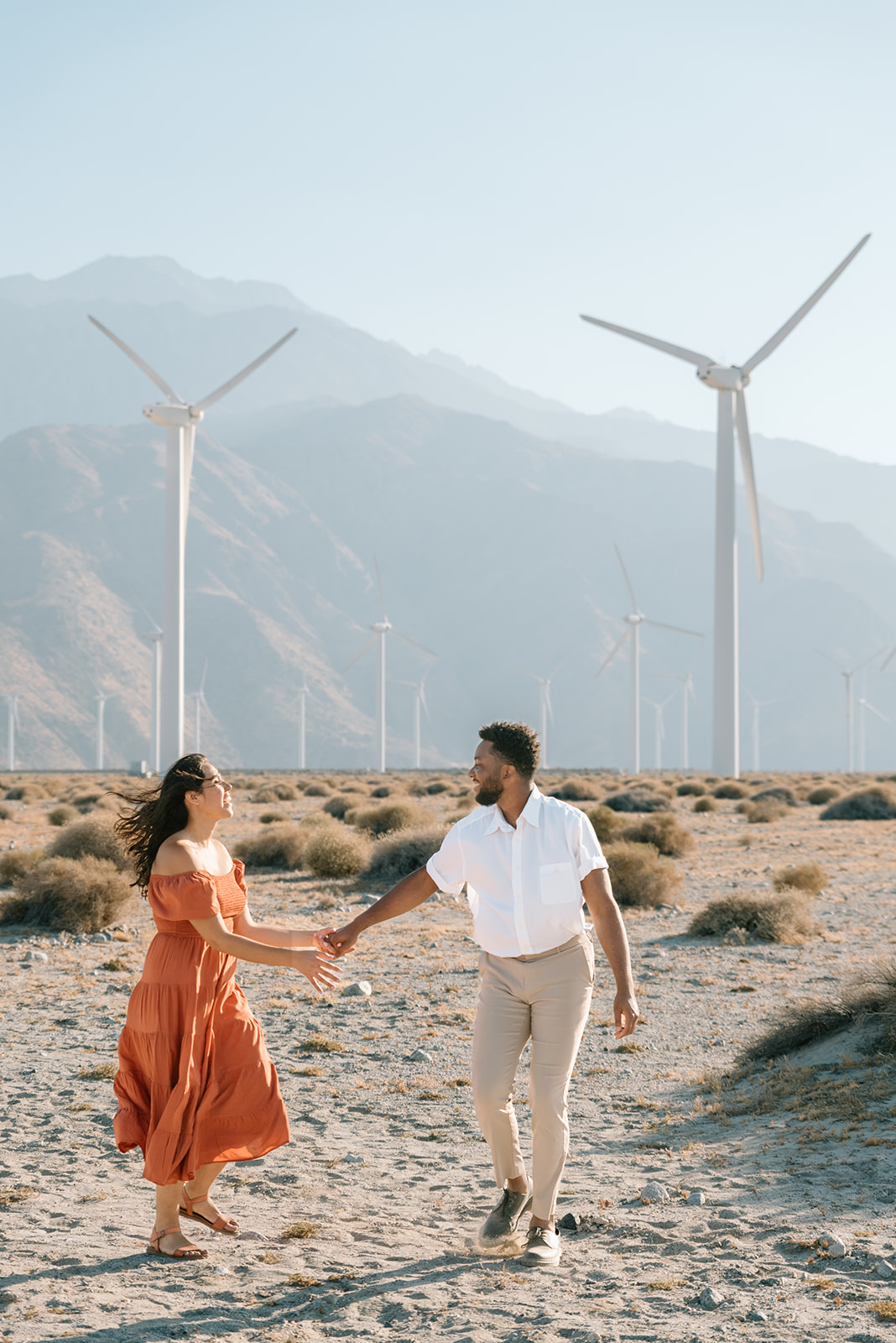Wind turbines blow in the wind behind engaged couple