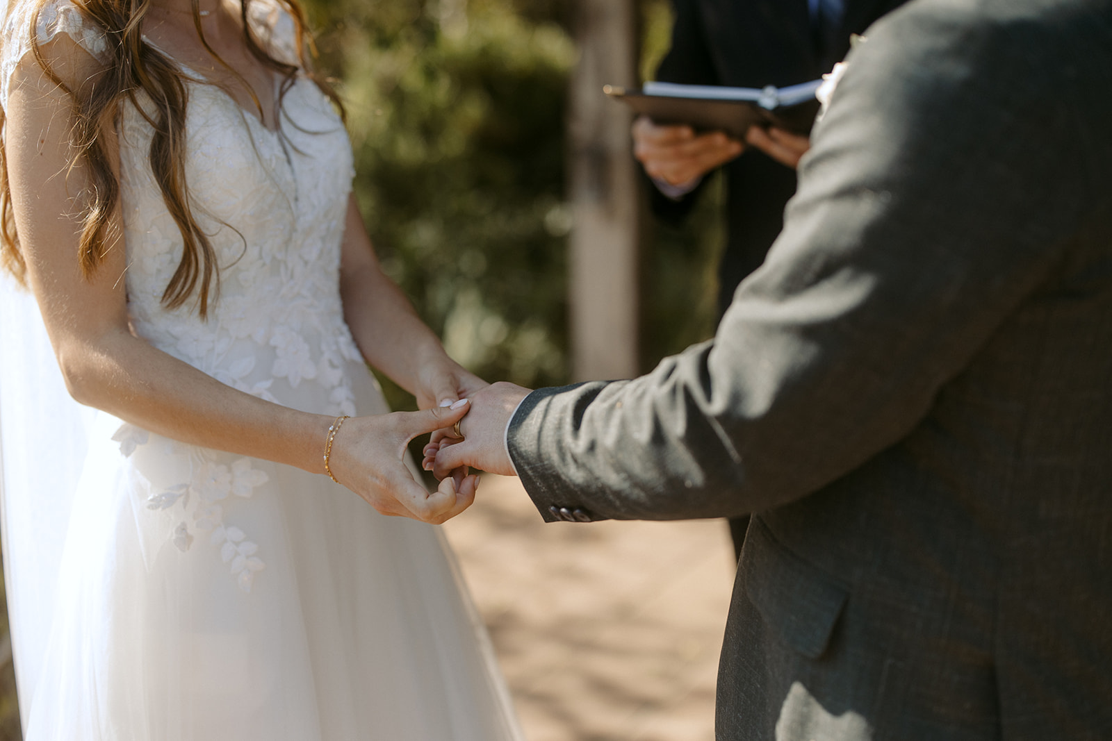 Bride puts ring on grooms finger during wedding ceremony at La Arboleda in California