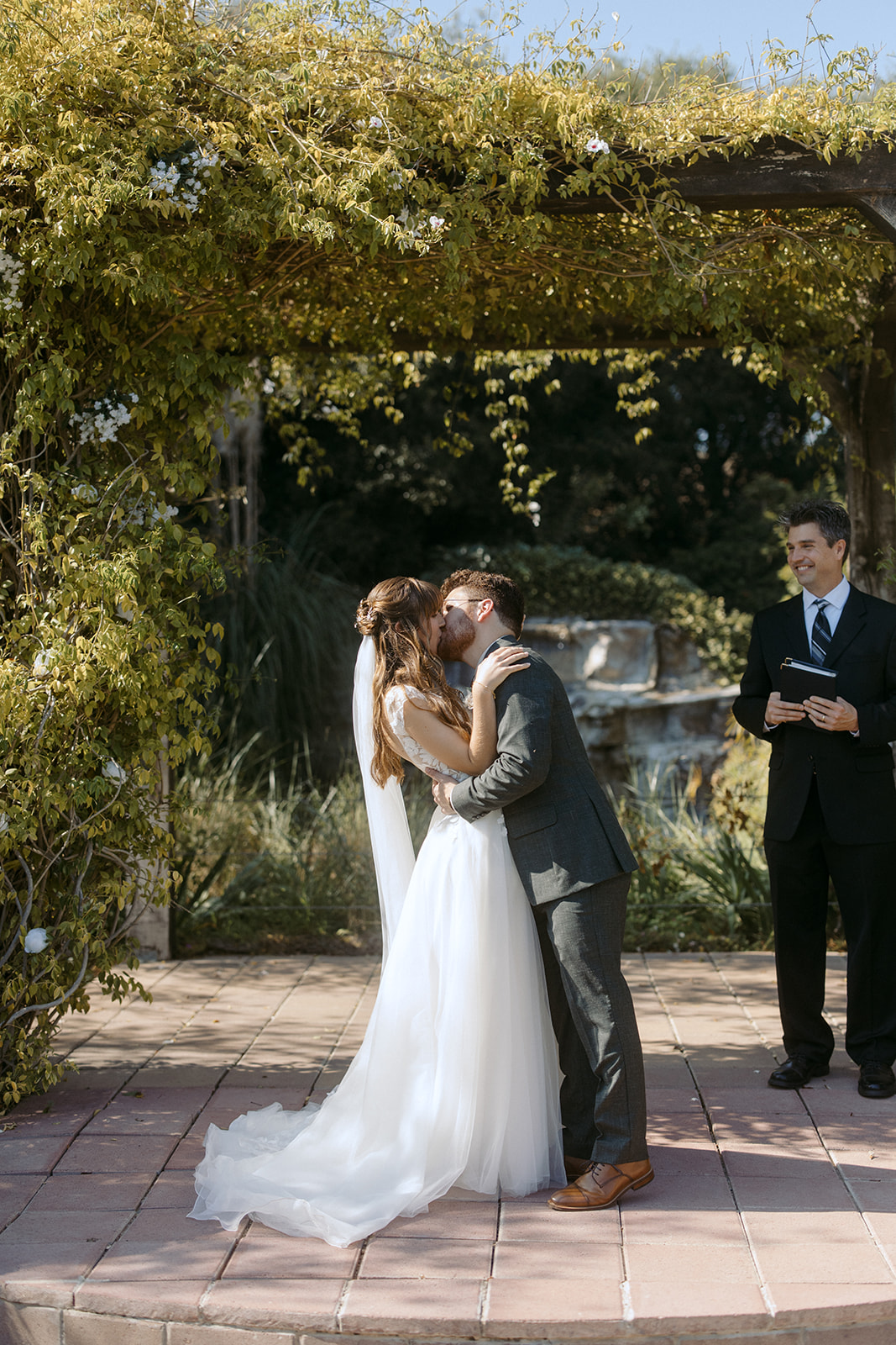 Bride and groom kissing to conclude wedding ceremony at La Arboleda in California