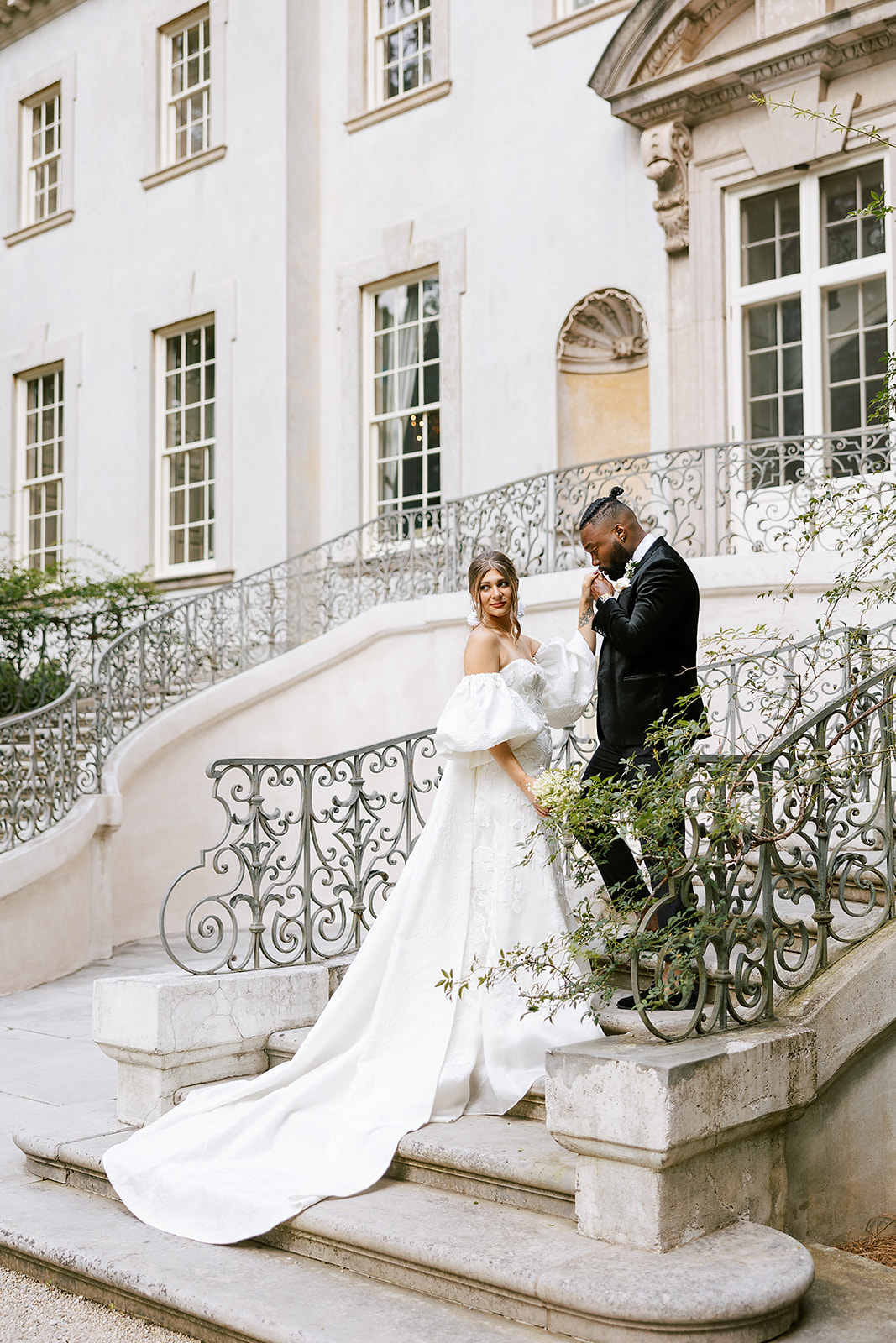 BRIDE AND GROOM ON THE STEPS OF THE SWAN HOUSE IN ATLANTA, GA FOR AN EDITORIAL SHOOT KISSING HAND