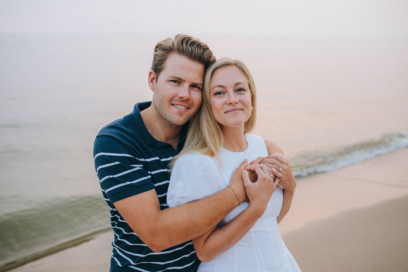 A timeless portrait of a couple holding one another on the beach during engagement photos at Lake Michigan