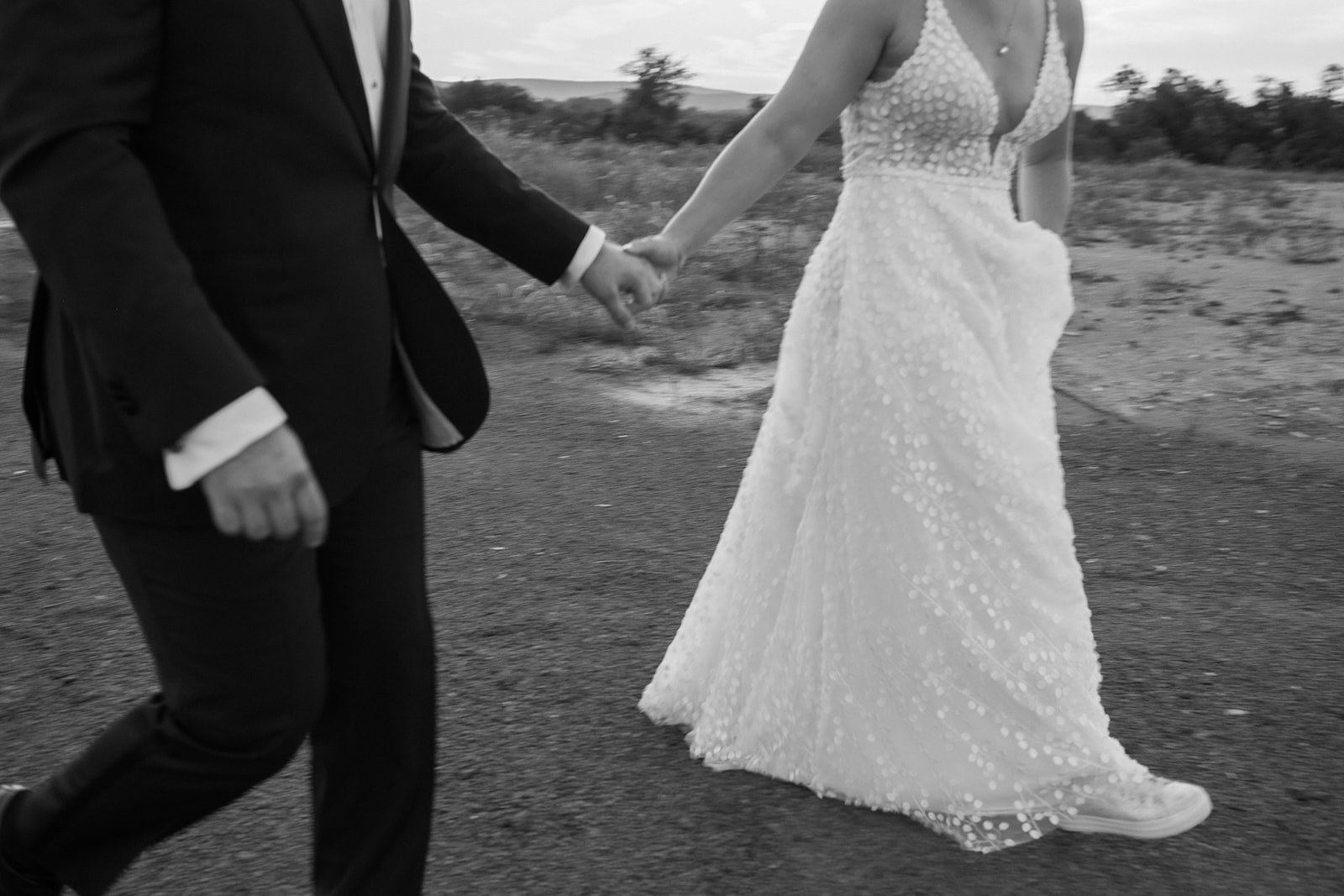Bride and groom hold hands and walk back to their reception after sunset portraits