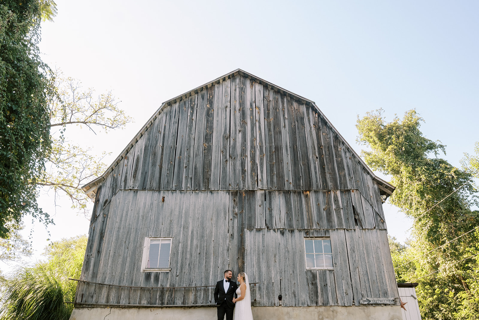 Bride and groom stand in front of a huge old barn at Virginia wedding