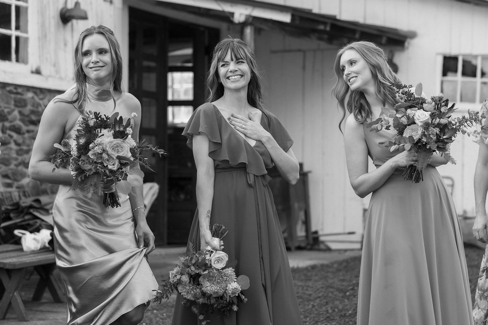 Bridesmaids laugh together holding their bouquets in between portraits