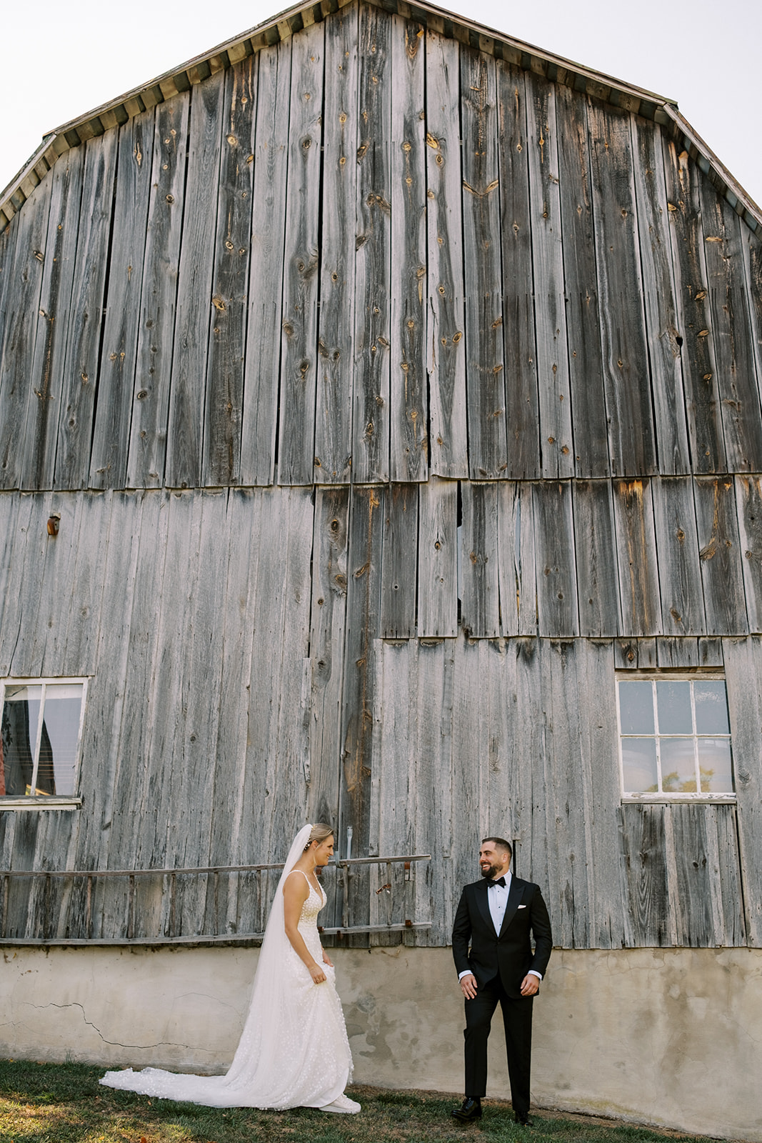 Groom turns around in front of an old barn to see his bride during their Loudoun County wedding first look