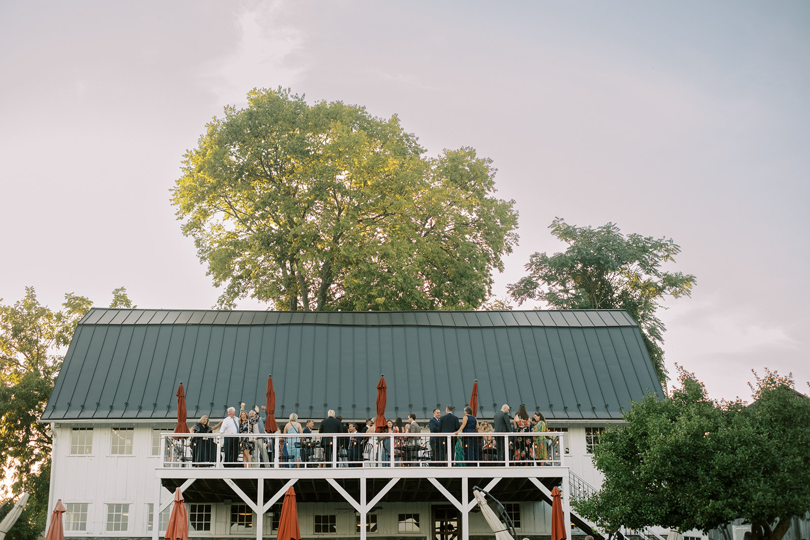 Guests during cocktail hour on the deck of an old barn at Virginia barn wedding