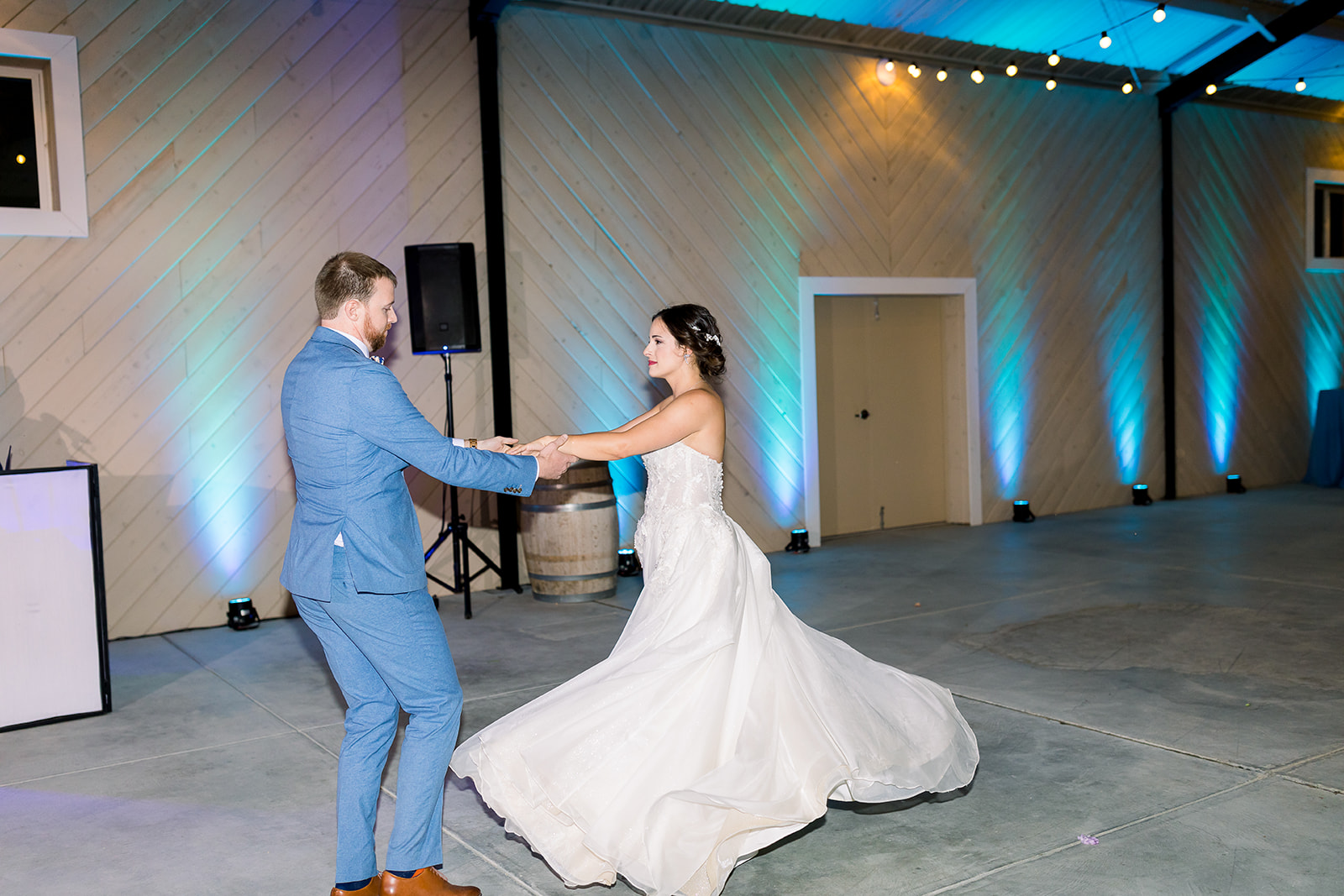 Bride's creamy train swirls as she joyfully dances with her groom at Willow and Oak.