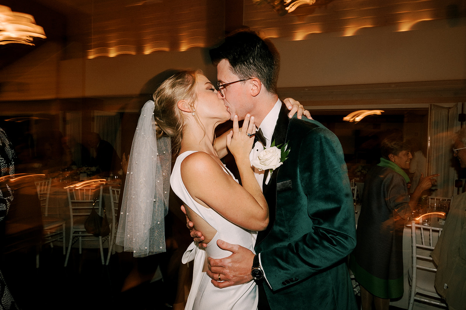 bride and groom kiss during their reception while dancing on the floor