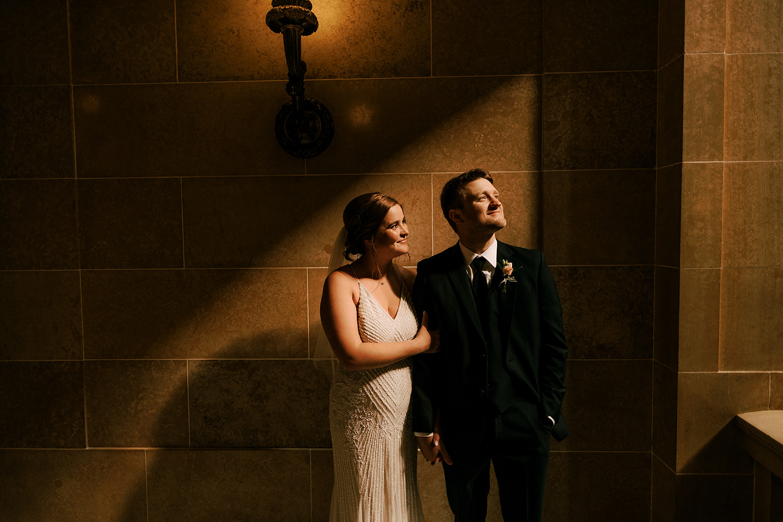 bride and groom stand in dramatic light on their wedding day at the wisconsin state capitol building