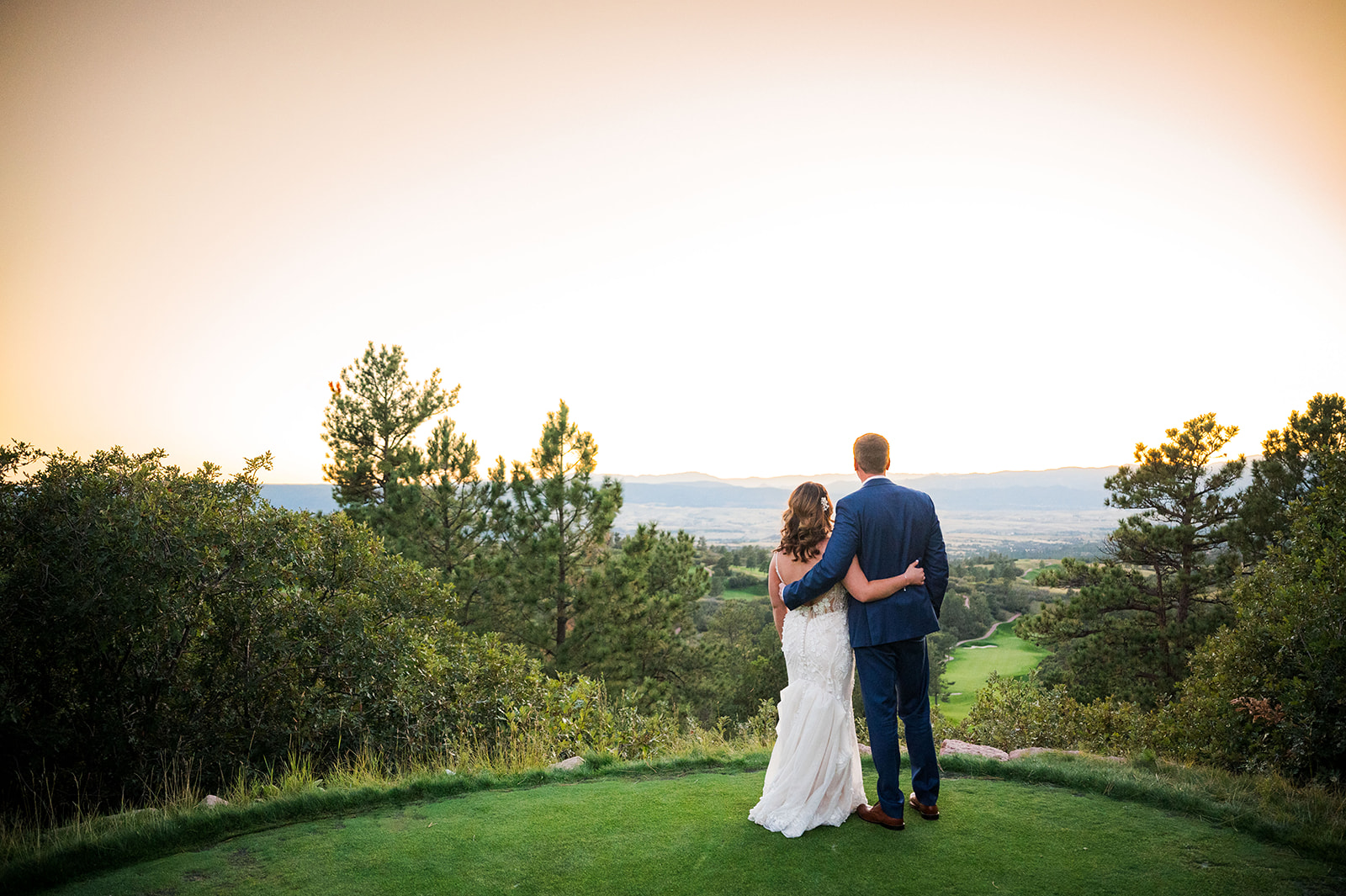The bride and groom faced away from the camera looking out at the Colorado landscape at golden hour.