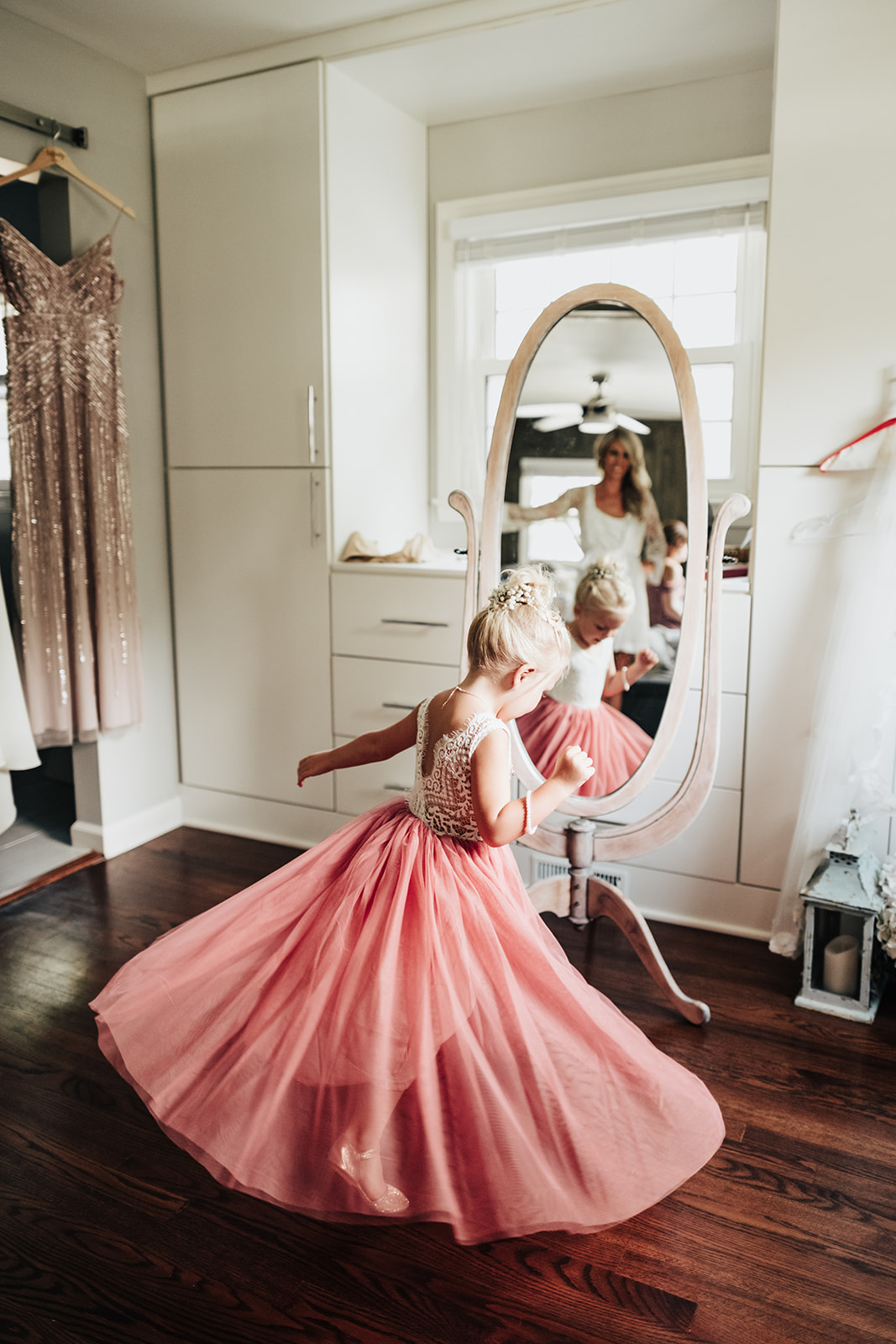 Little girl twirls in her flower girl dress infant of mirror