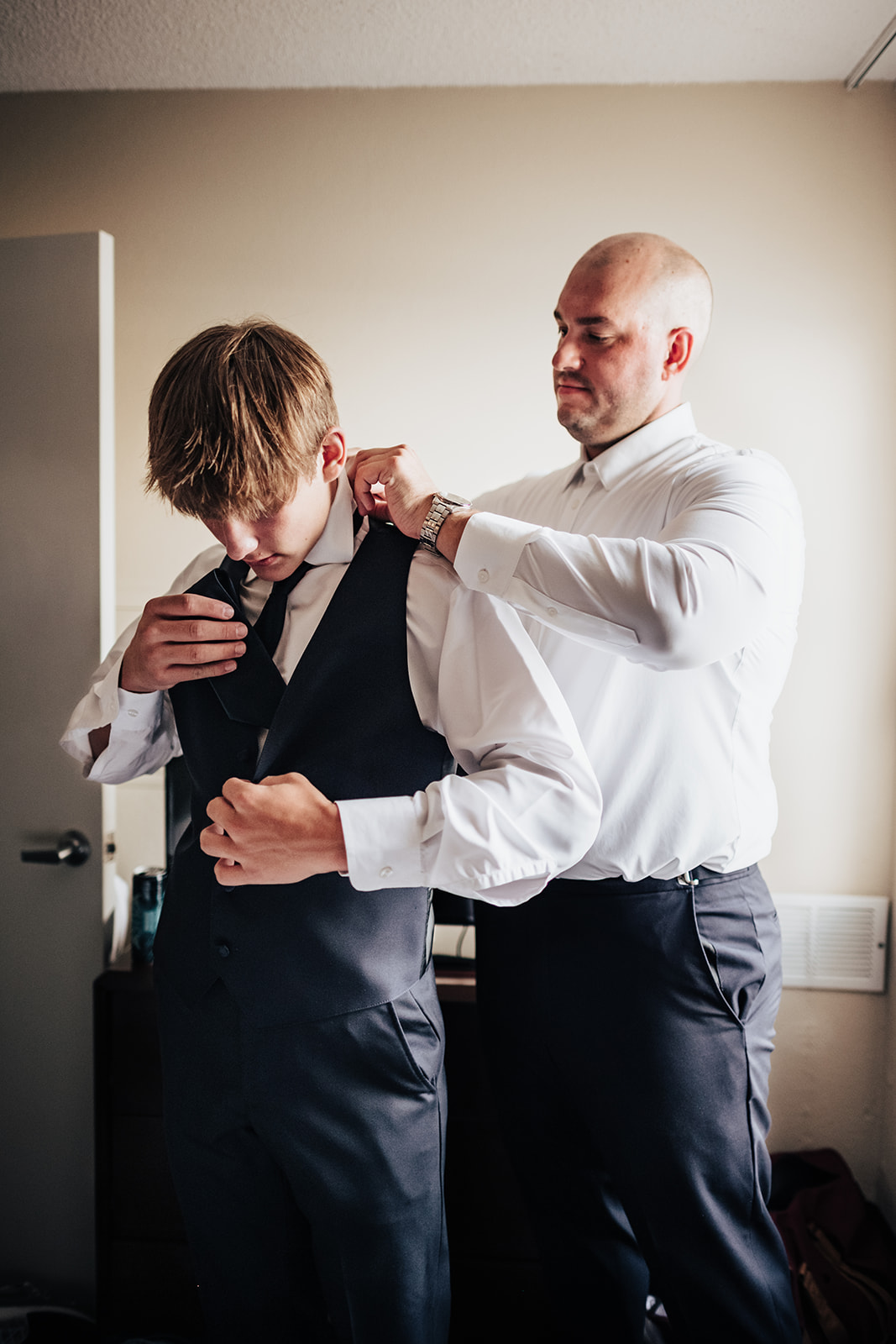Groom helps son of bride get dressed for wedding day