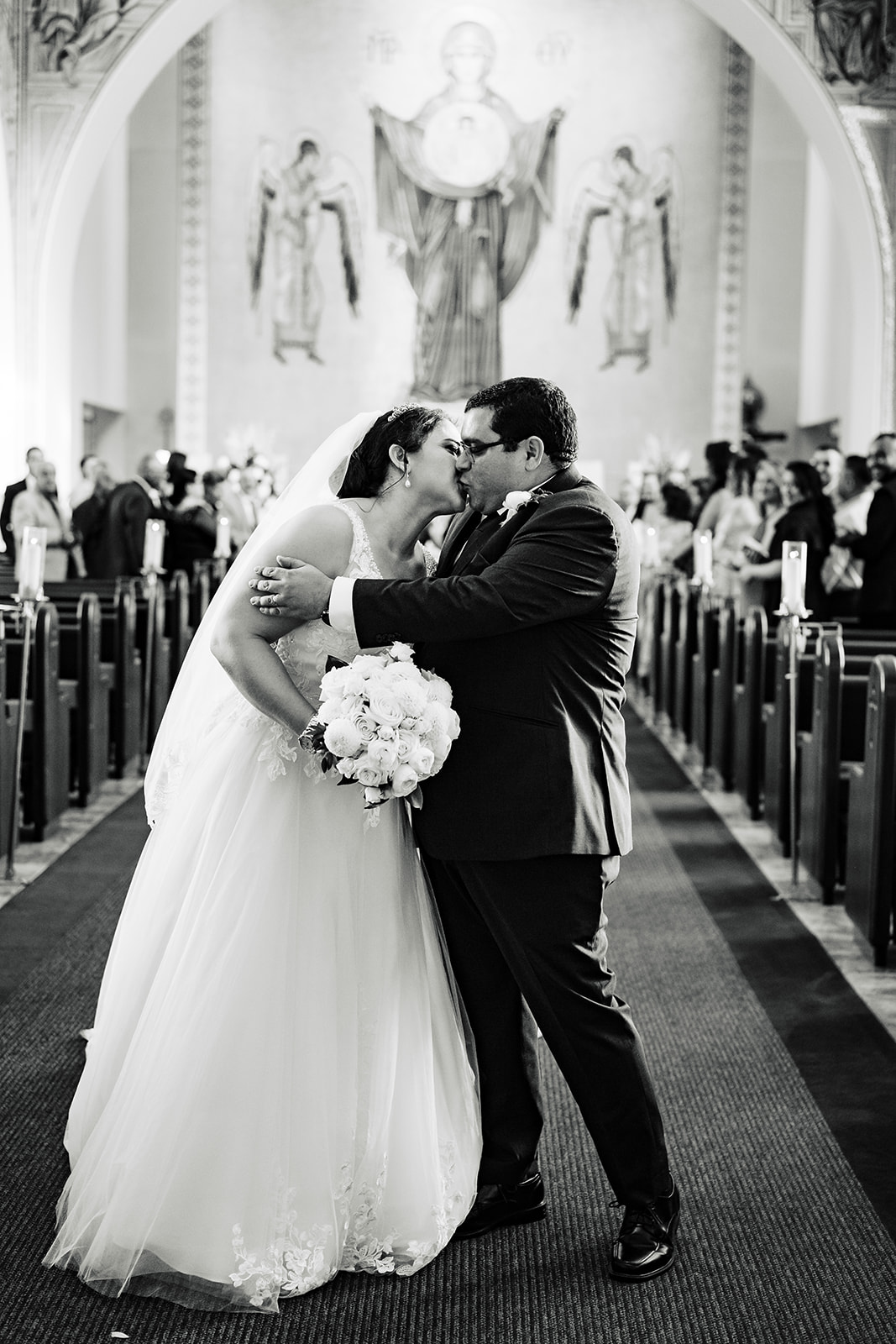 bride and groom kiss at the end of the aisle after their ceremony recessional