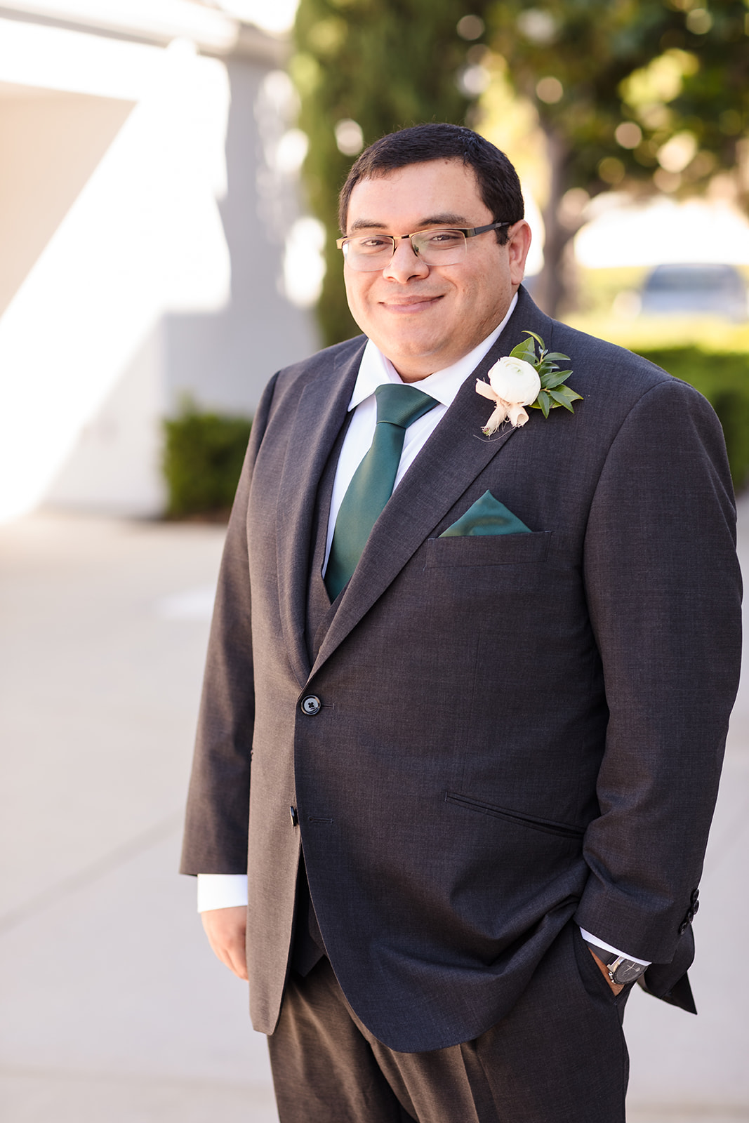 Groom's grey suit with green tie and white floral boutinniere
