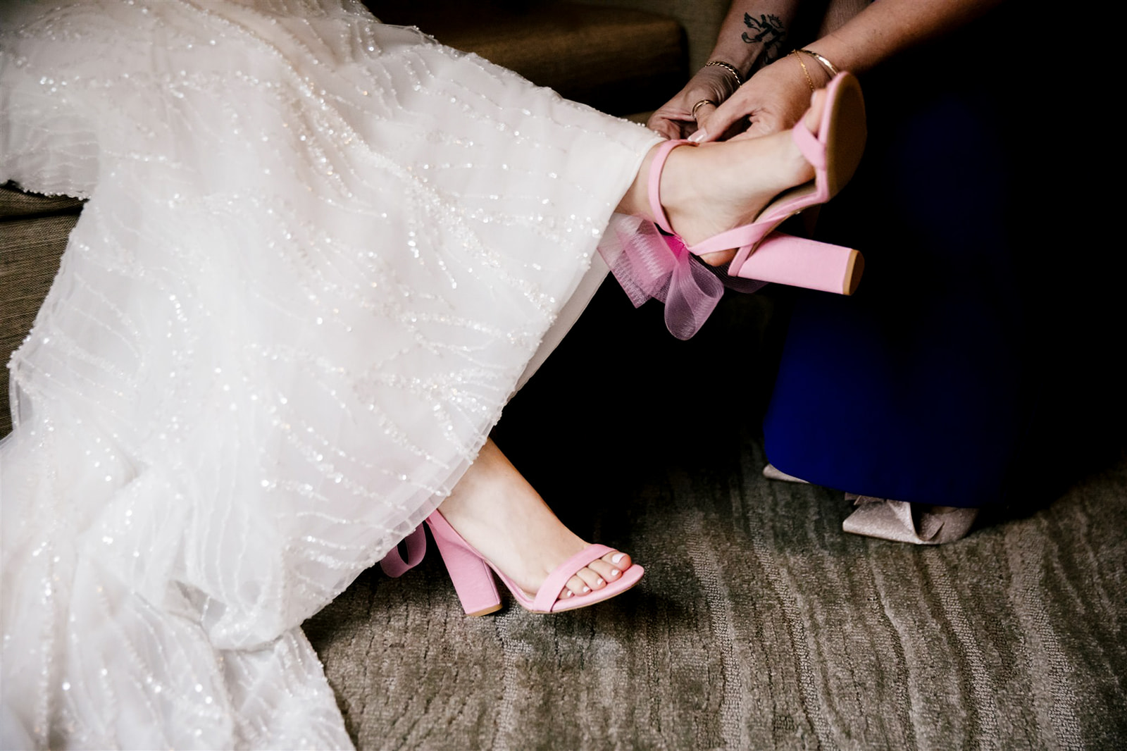 Bride's pink shoes add a pop of color to her getting ready moments, infusing a playful charm into the day.