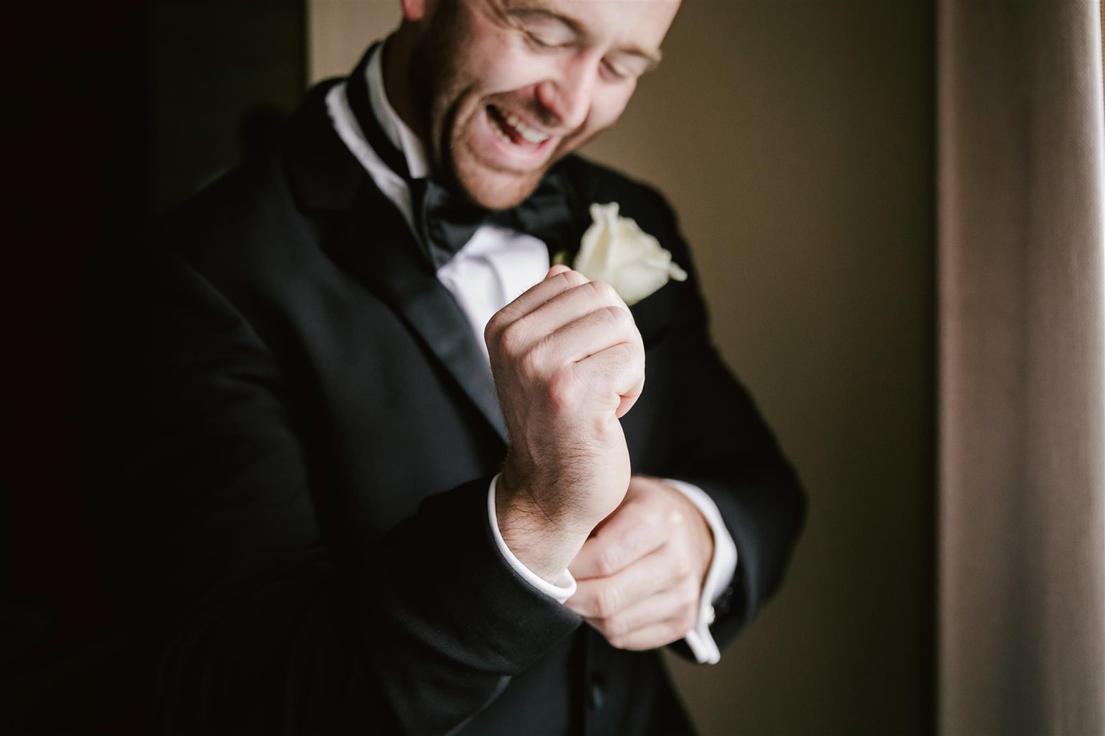 As the groom prepares for the wedding, he meticulously adjusts his cufflinks, adding a final touch of elegance.