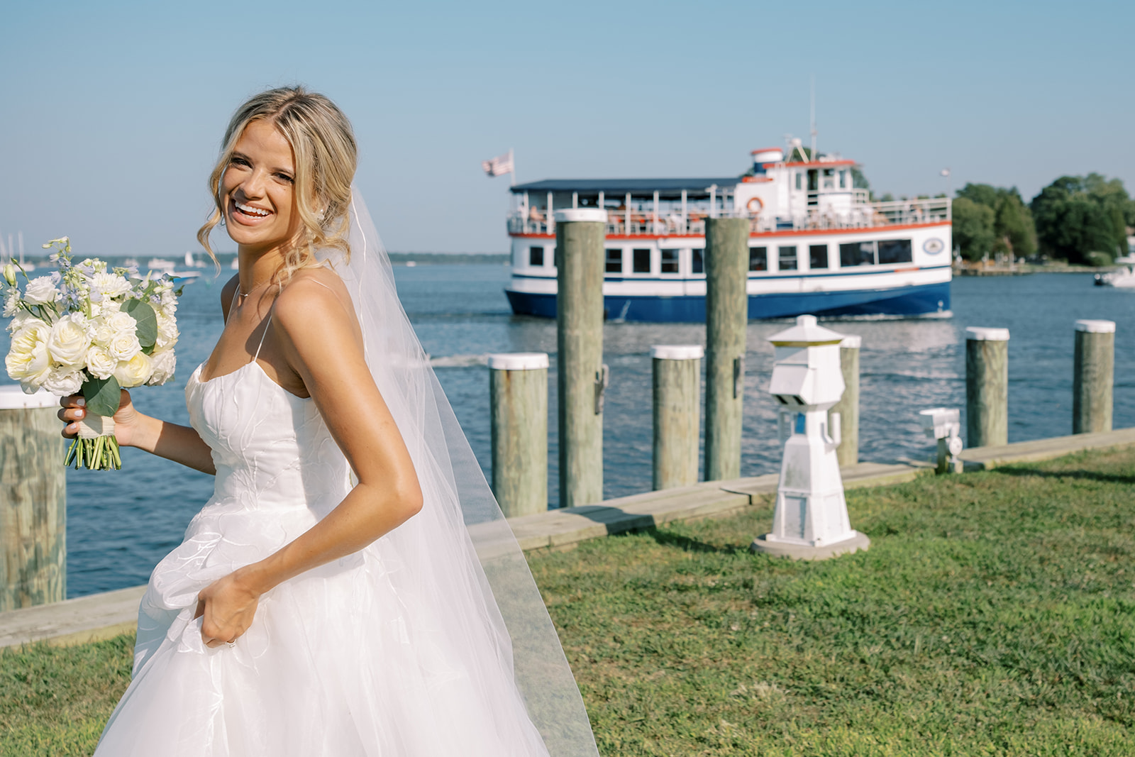 bride walking with a boat passing by on the bay at chesapeake bay maritime museum