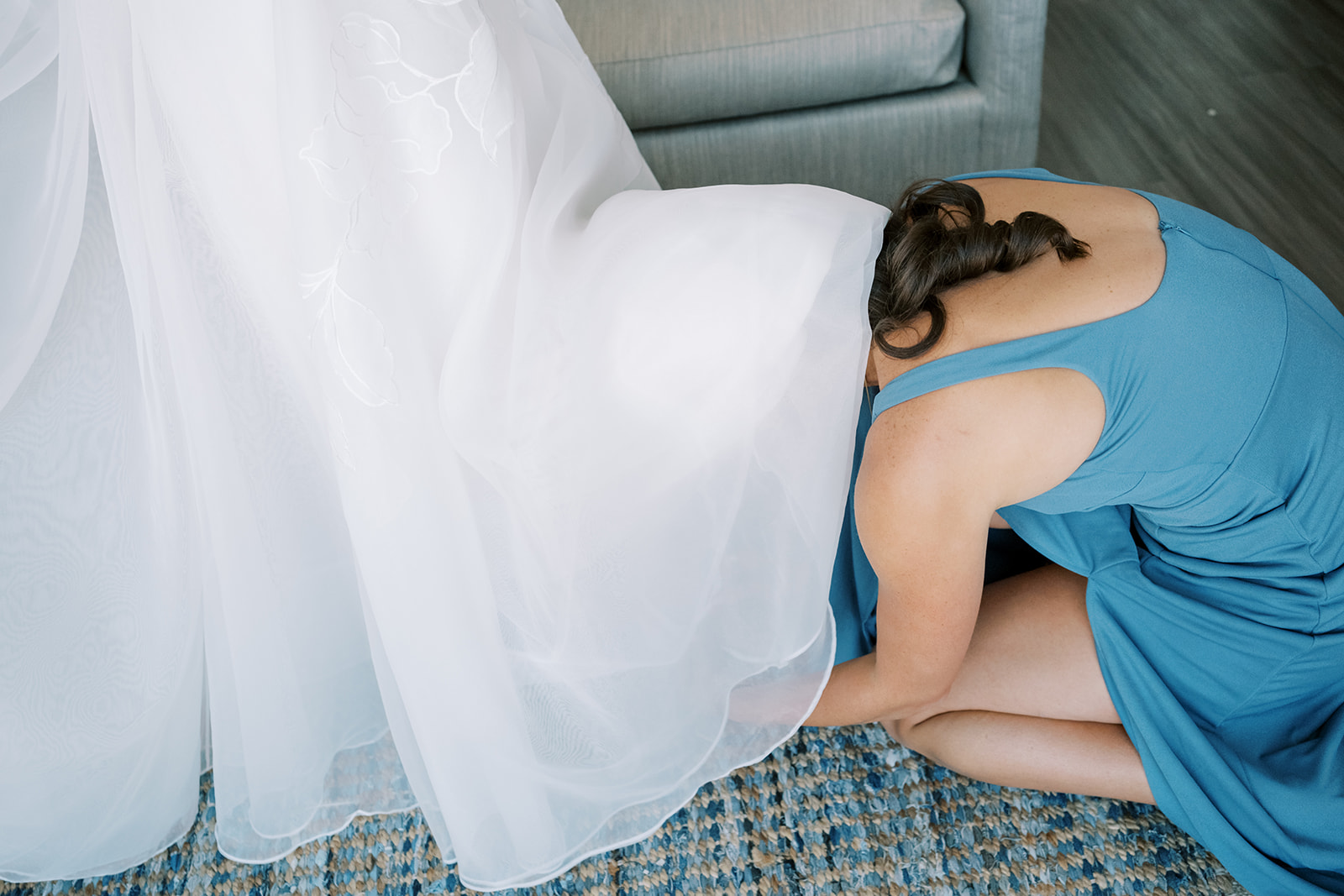 maid of honor puts on shoes underneath the wedding dress at saint michaels wedding