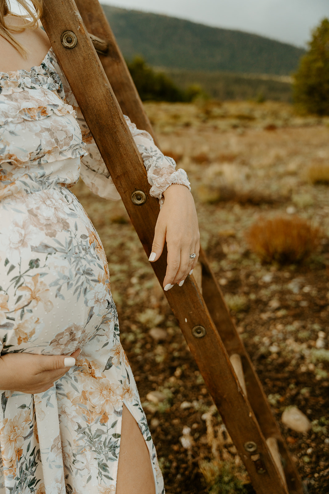 a detail of a moms belly nestled on a wooden ladder during fall maternity photos 