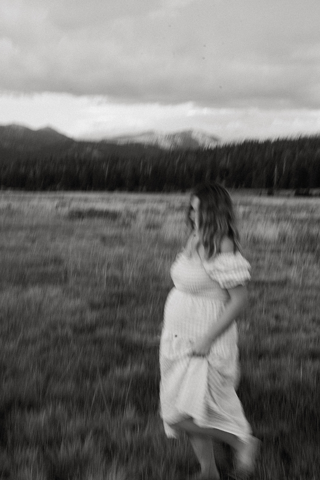 a mom holding flowers in a black and white whimsical artistic blurred maternity photos taken in hope valley california.