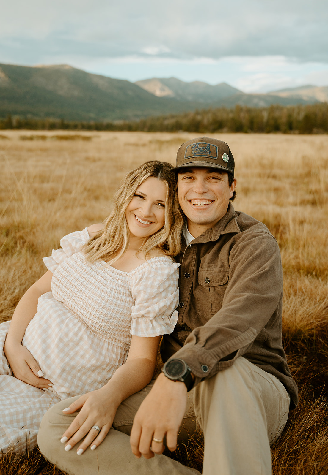 a romantic portrait of a couple snuggled up in a field during their maternity photoshoot. 