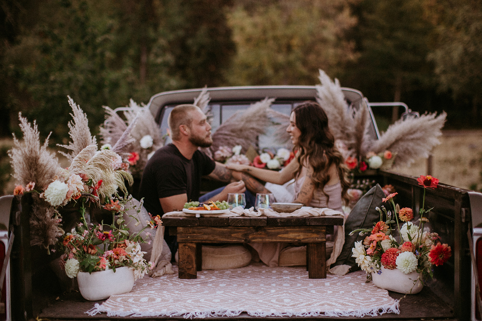 Couple enjoying a picnic in the bed of his truck for tailgate date with florals