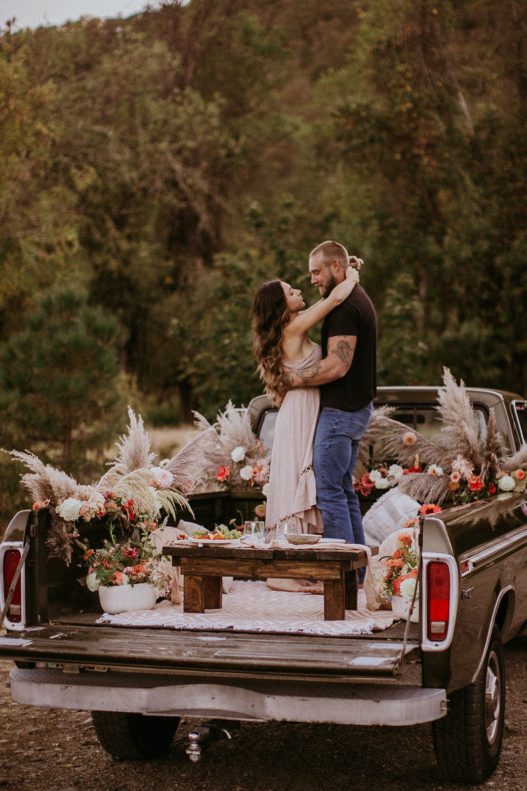 Couple enjoying a picnic in the bed of his truck for tailgate date with florals
