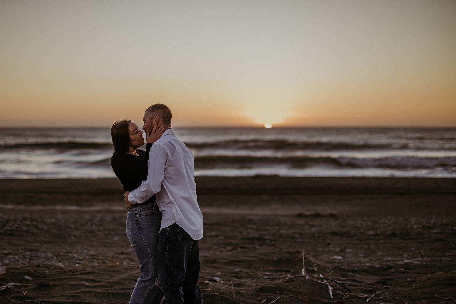 Couple at their engagement session on the wild California coast during golden hour