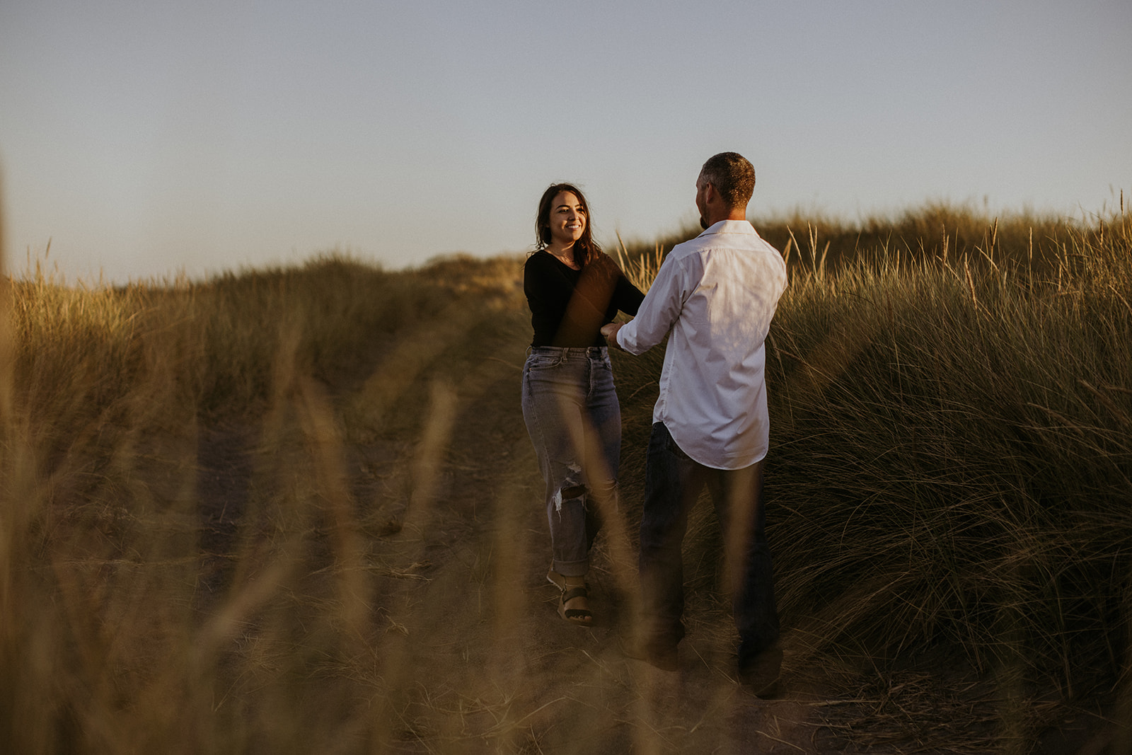 Couple at their engagement session on the wild California coast during golden hour