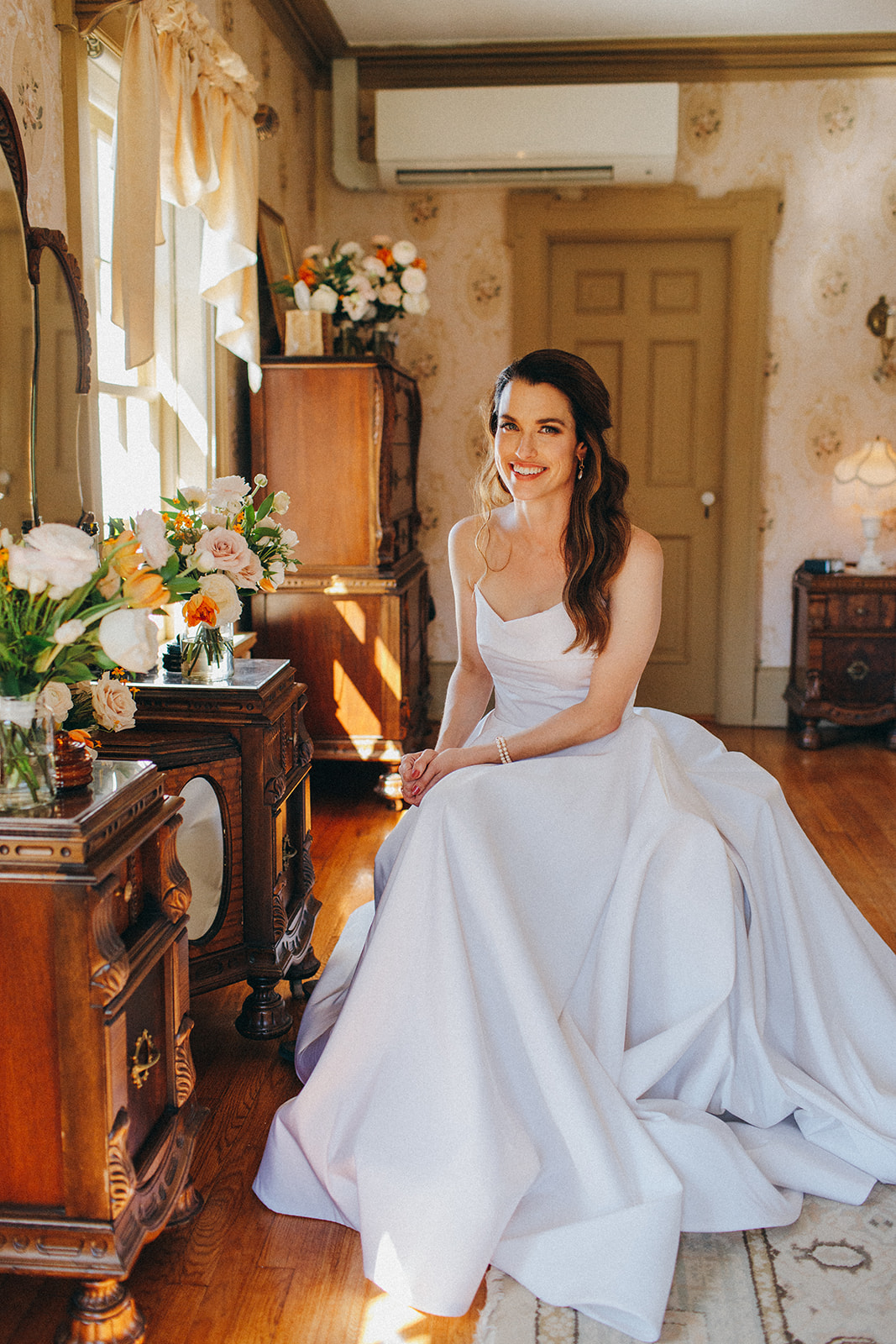 A timeless bridal portrait of a bride sitting in her Sarah Seven gown in the Felt Mansion